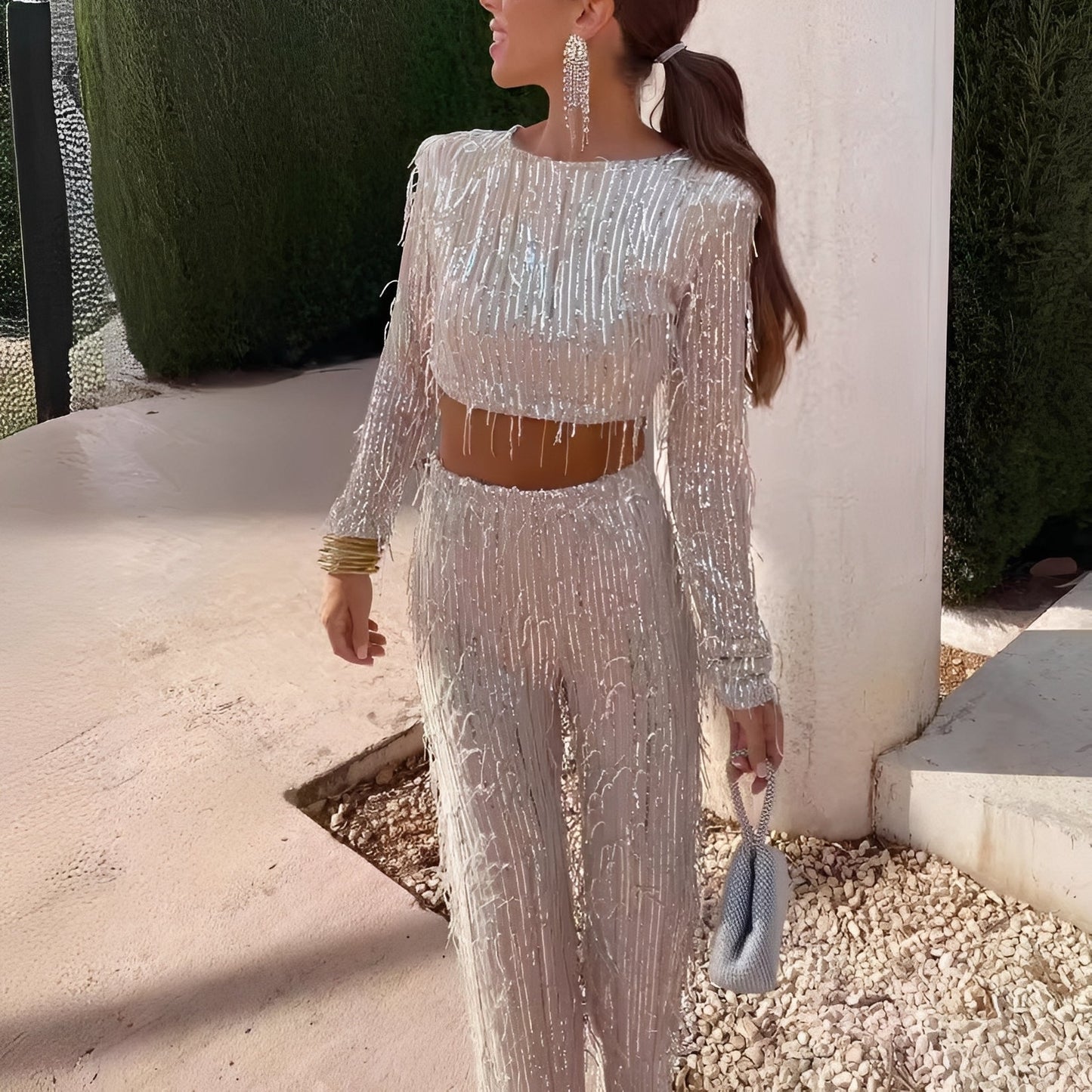 Woman in a sparkling outfit holding a handbag outdoors.