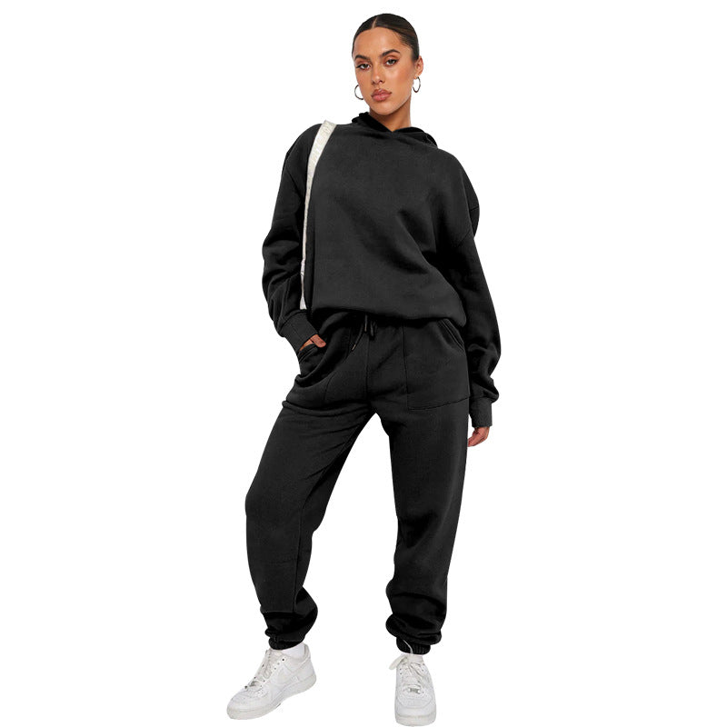 Person wearing a black tracksuit with white sneakers on a white background