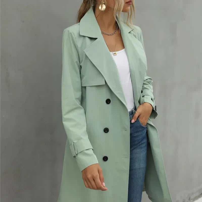 Person wearing a light green trench coat against a gray background