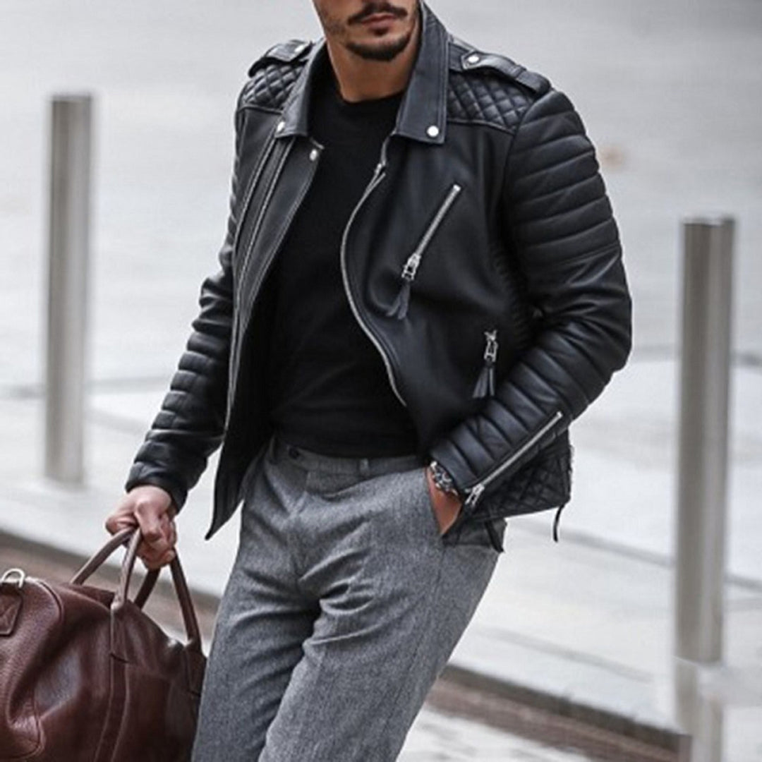 Man wearing a black leather jacket and gray pants, holding a brown leather bag.