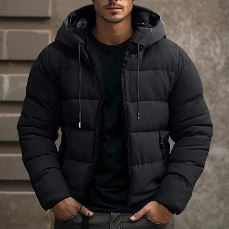 Man wearing a black puffer jacket against a neutral background