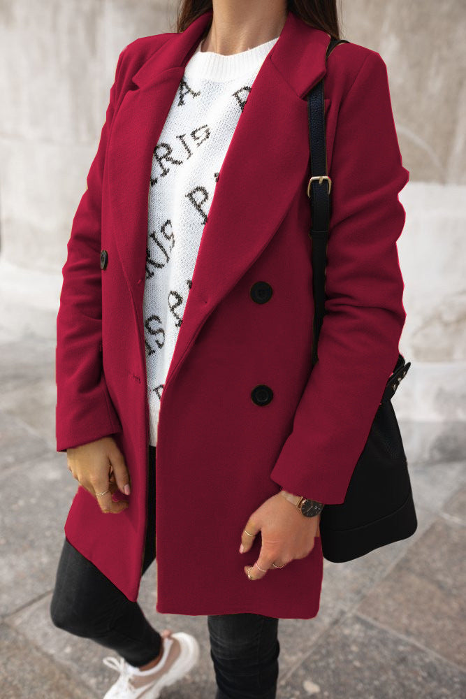 Person wearing a red coat over a white graphic t-shirt, standing on a stone pavement.