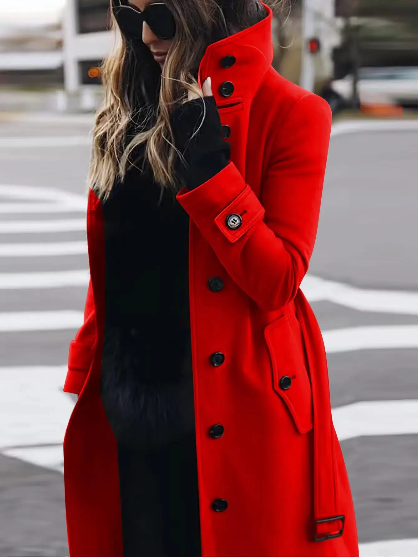 Person wearing a red coat and black gloves on a city street.