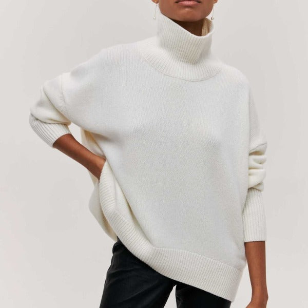 Person wearing a white turtleneck sweater against a plain background