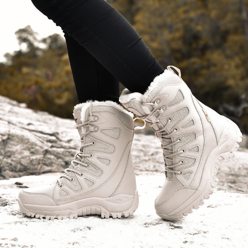 White winter boots with fur lining worn by a person on a snowy ground.