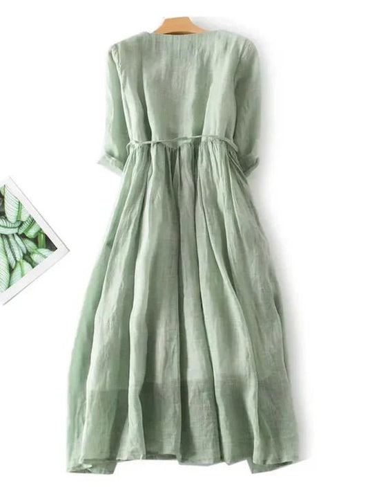 Green dress on a wooden hanger against a white background