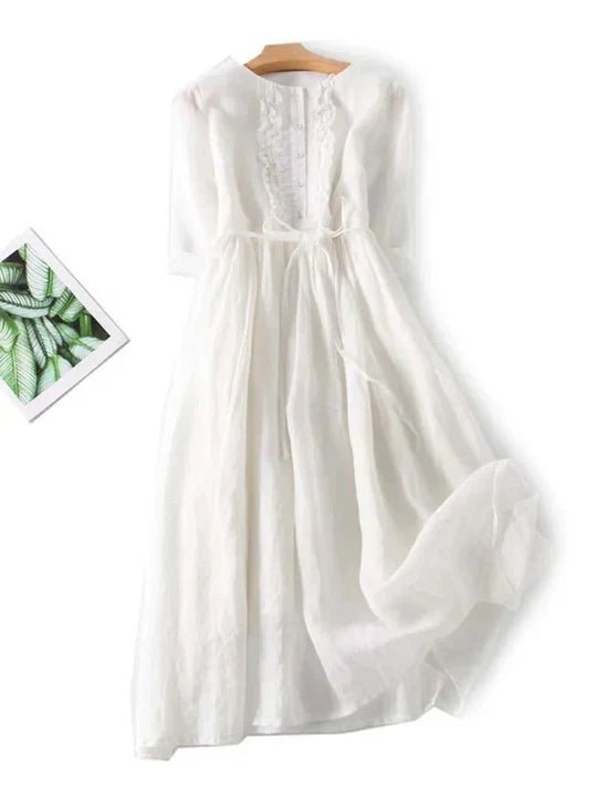 White dress on a hanger with a small inset of green leaves.