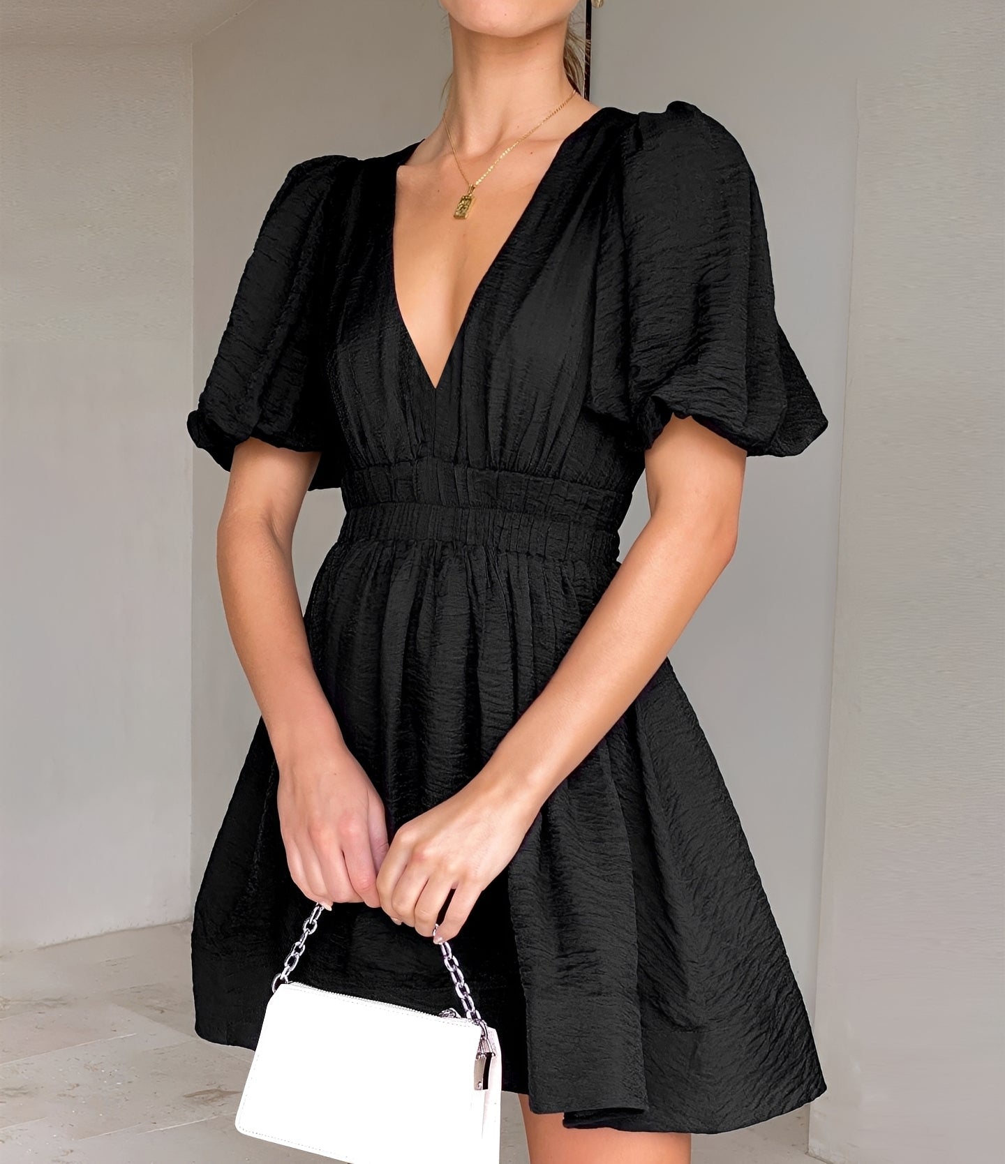 Woman wearing a black dress with puff sleeves against a plain background