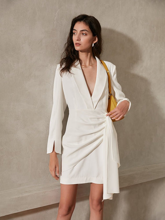Woman wearing a white dress with a yellow bag against a beige wall
