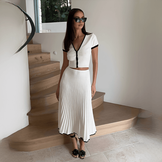 Woman in a white outfit with black accents standing on a staircase.