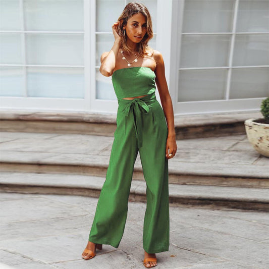 Woman wearing a green strapless jumpsuit standing on a wooden deck.