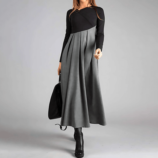 Person wearing a black and gray dress holding a black handbag on a gray background