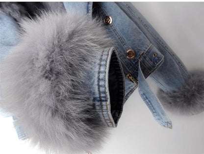 Denim jacket with gray fur pom-poms on a white background