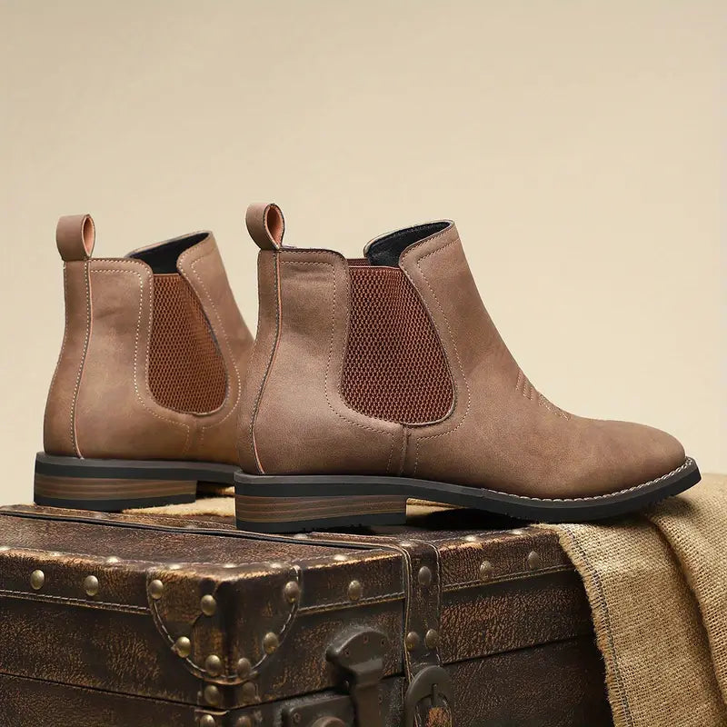 Pair of brown leather boots on a vintage suitcase with a beige background