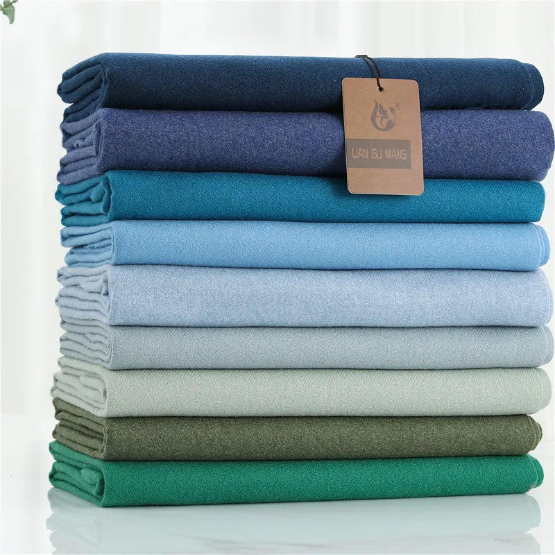 Stack of folded cloths in various blue and green shades with a brand tag on a white background