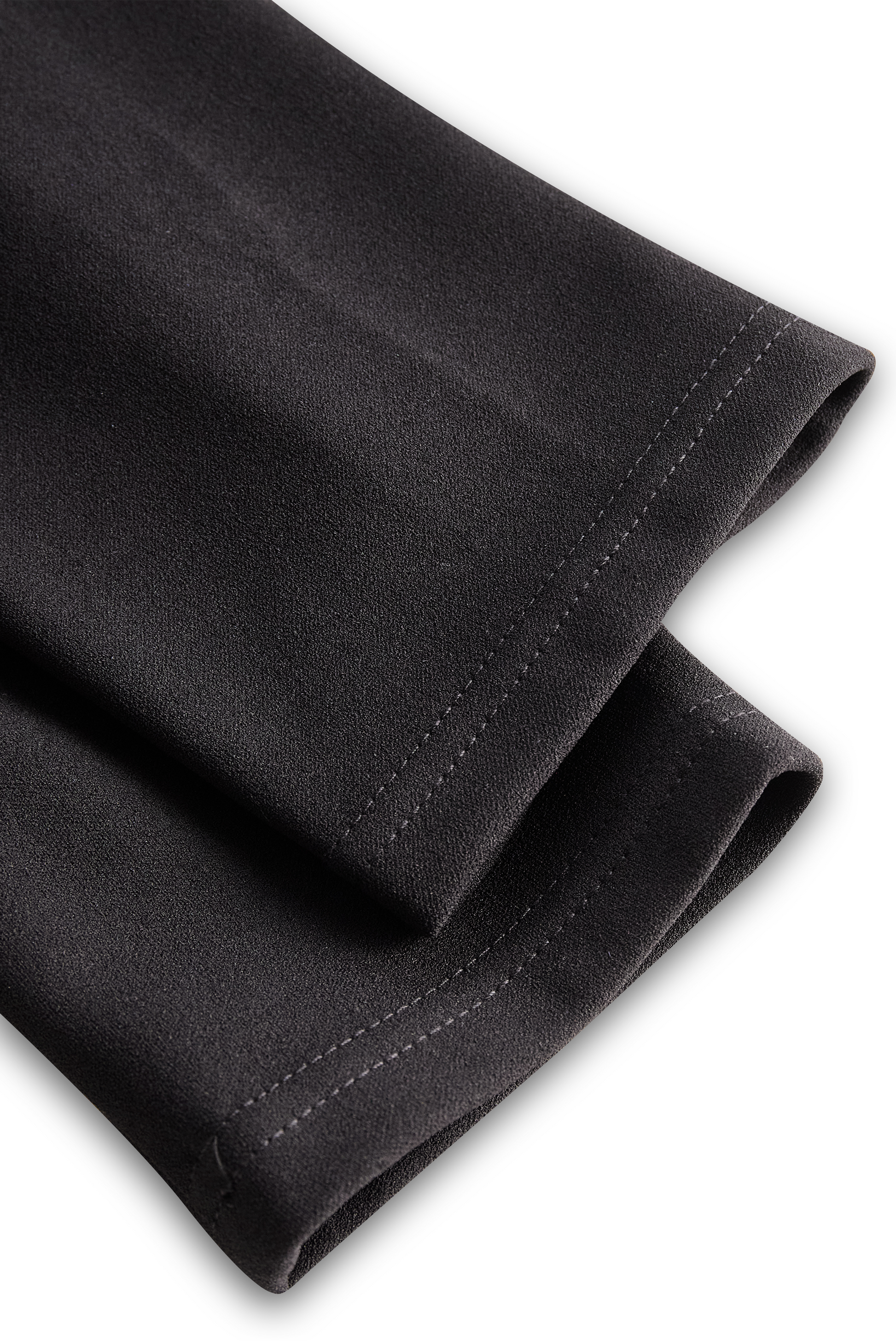 Close-up of black pants with a white background