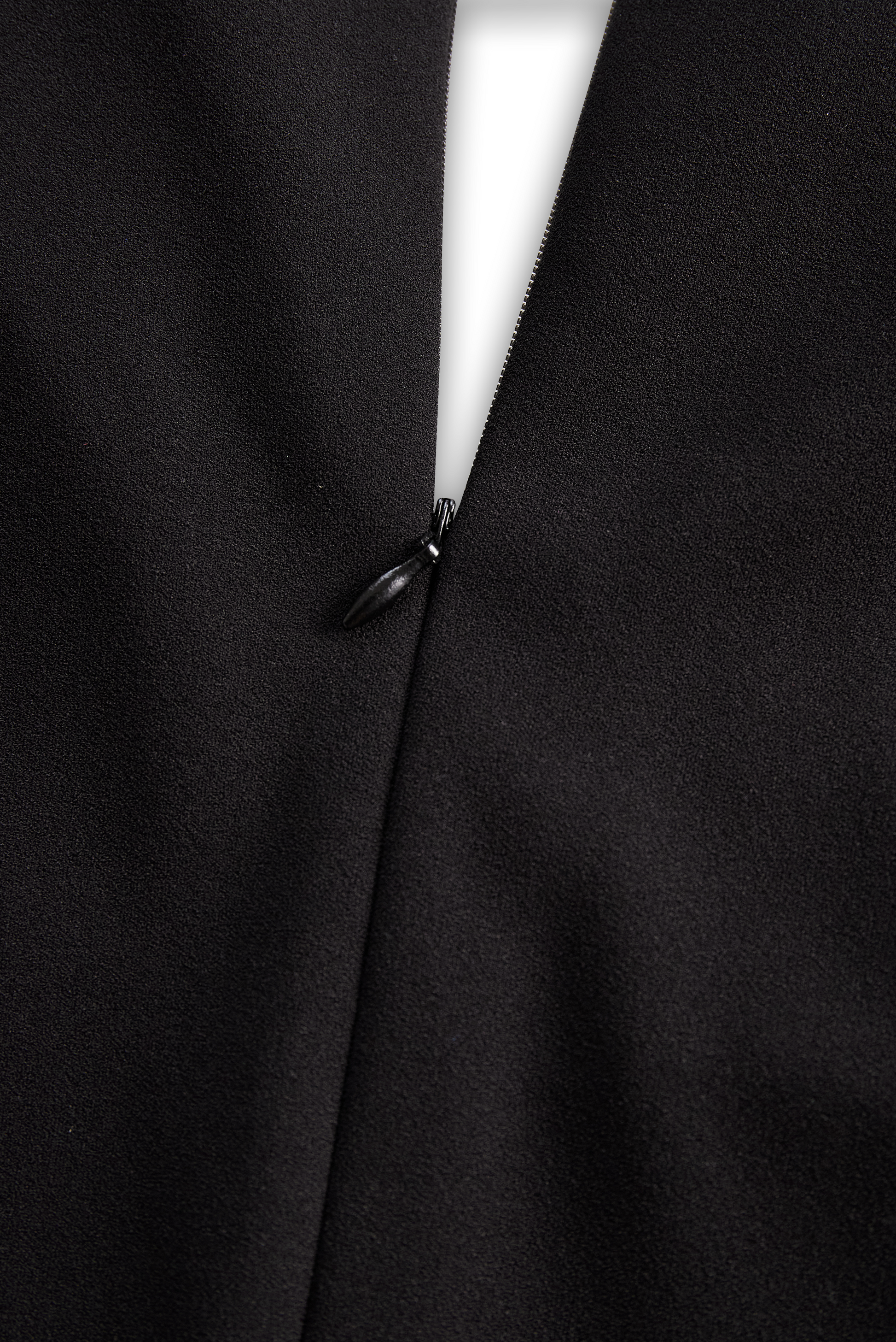 Close-up of a black coat with a button detail on a dark background