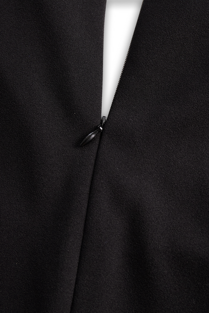 Close-up of a black coat with a button detail on a dark background