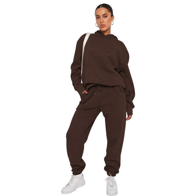 Person wearing a brown tracksuit with white sneakers on a white background
