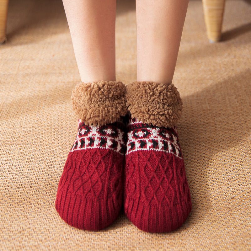 Red knitted socks with brown fuzzy tops on a beige carpet