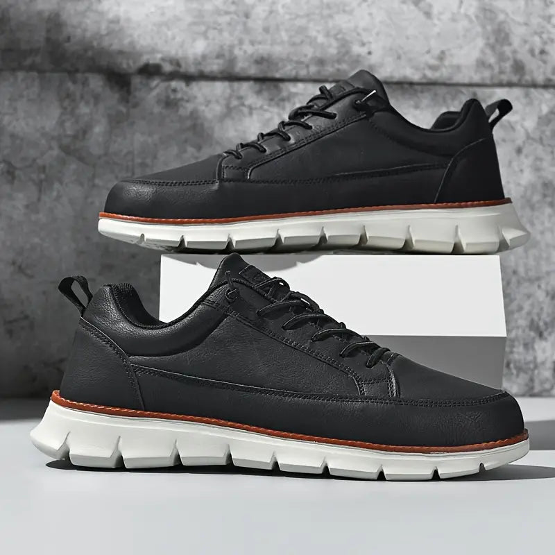 Black leather sneakers with white soles on a gray background