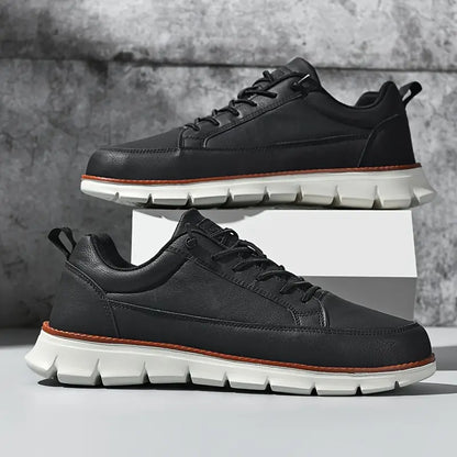 Black leather sneakers with white soles on a gray background