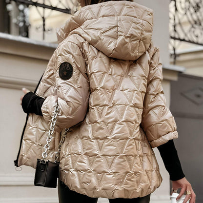 Person wearing a beige quilted jacket with a brand logo, holding a black handbag.