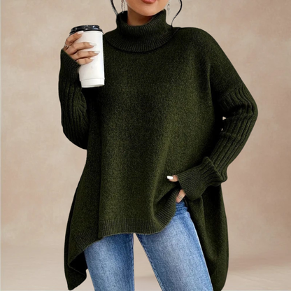 Person wearing a green sweater and blue jeans holding a white cup against a beige background