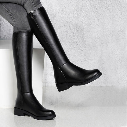 Black knee-high boots worn by a person on a light gray background