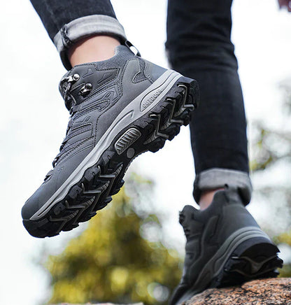 Gray hiking boots with black soles worn by a person on a blurred natural background
