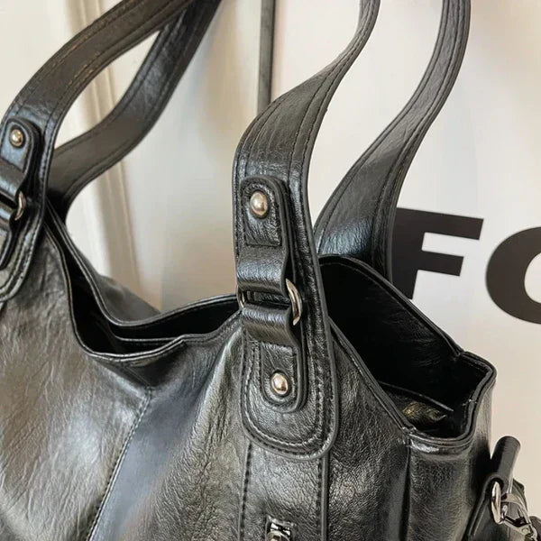 Close-up of a black leather handbag with visible brand logo.