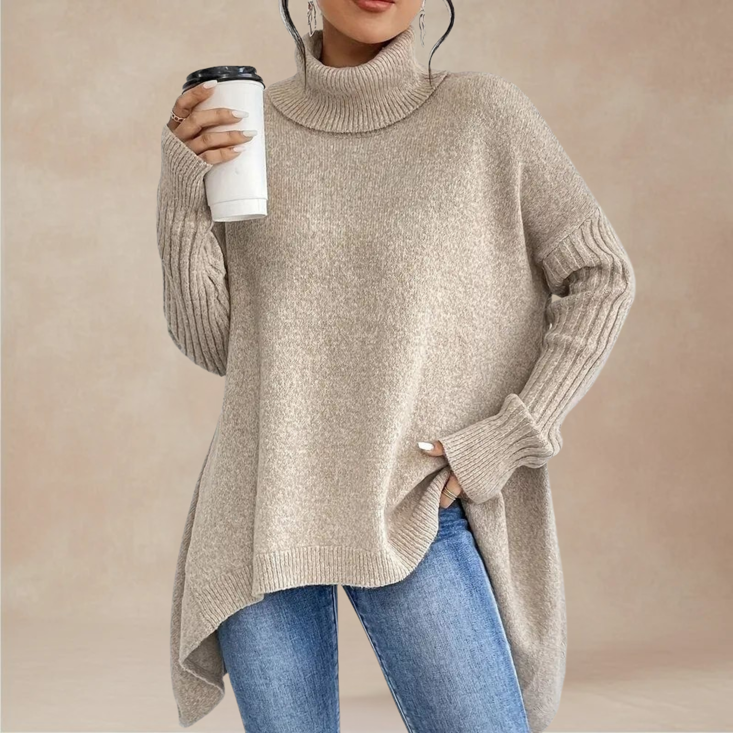 Person wearing a beige turtleneck sweater and blue jeans, holding a white cup with a black lid.