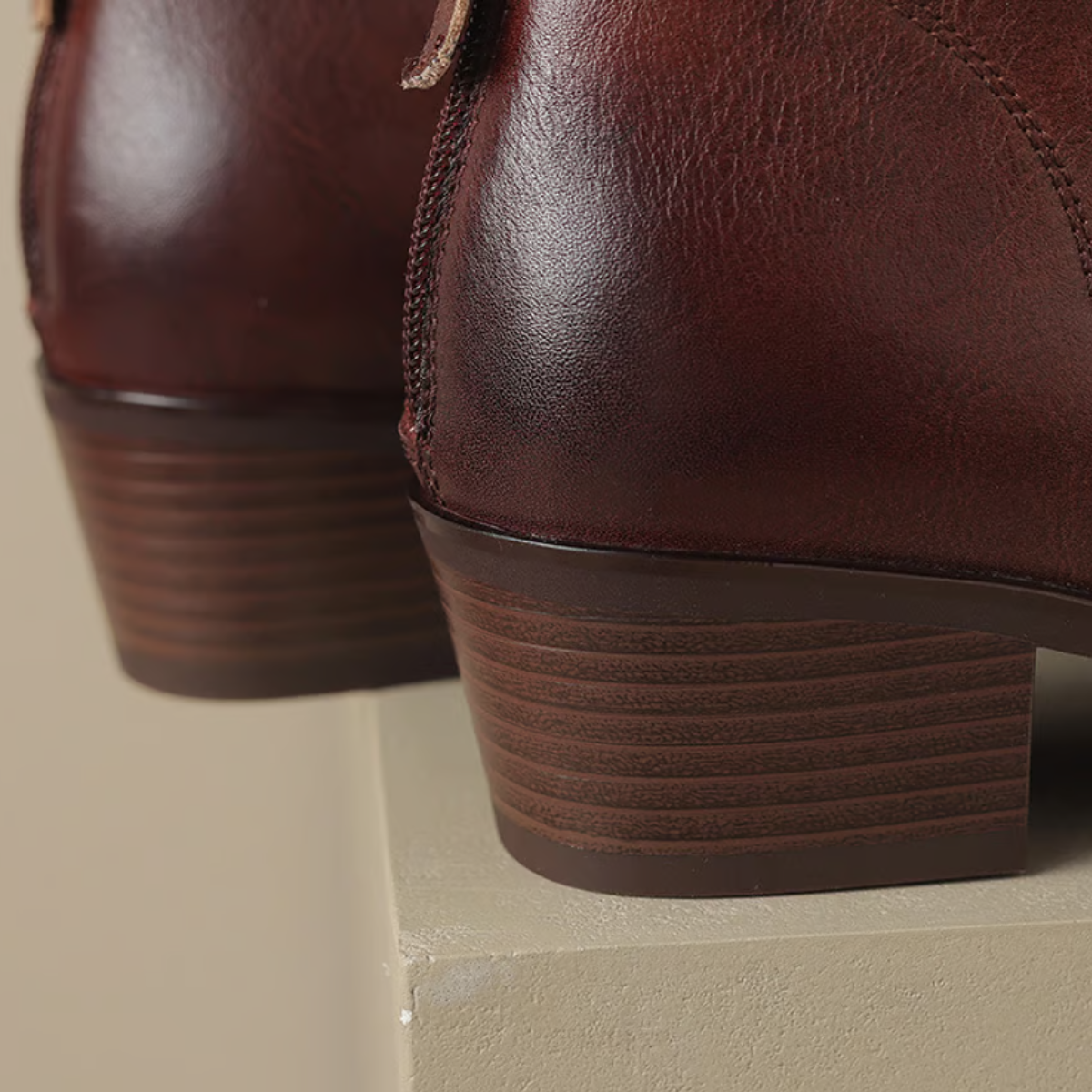 Close-up of brown leather boots with a beige background