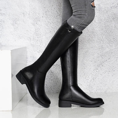 Black knee-high boots worn with gray pants on a light background
