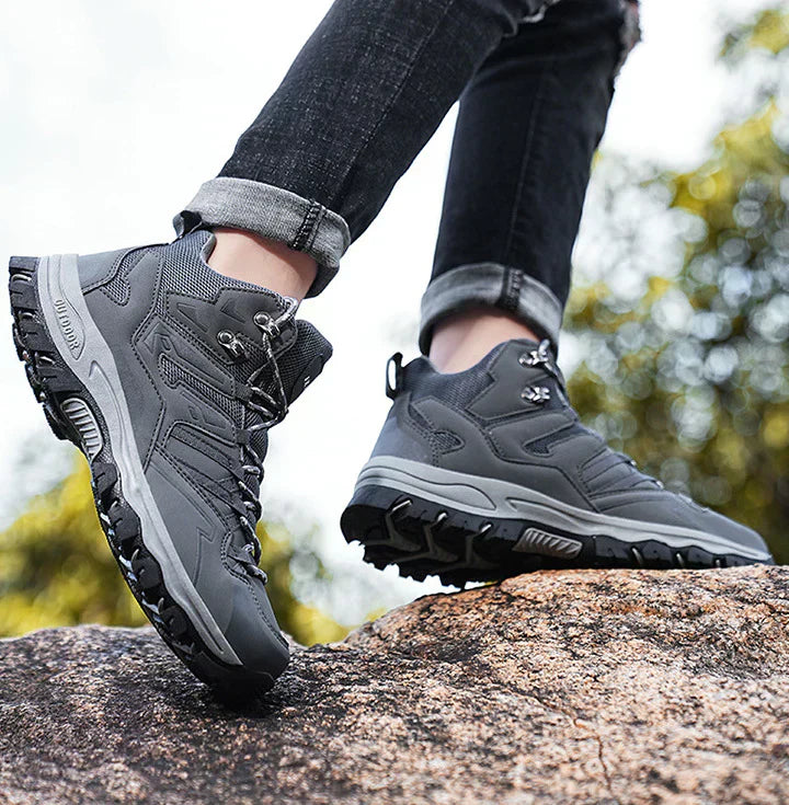 Person wearing gray hiking boots on a rock with a blurred natural background