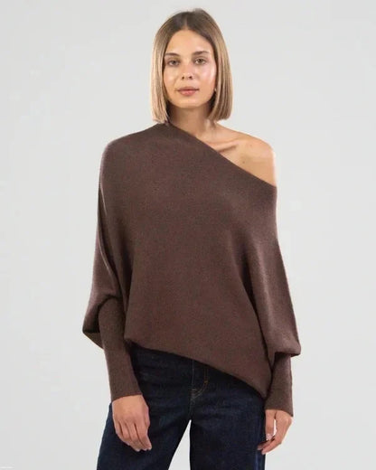 Woman wearing a brown one-shoulder sweater against a plain background