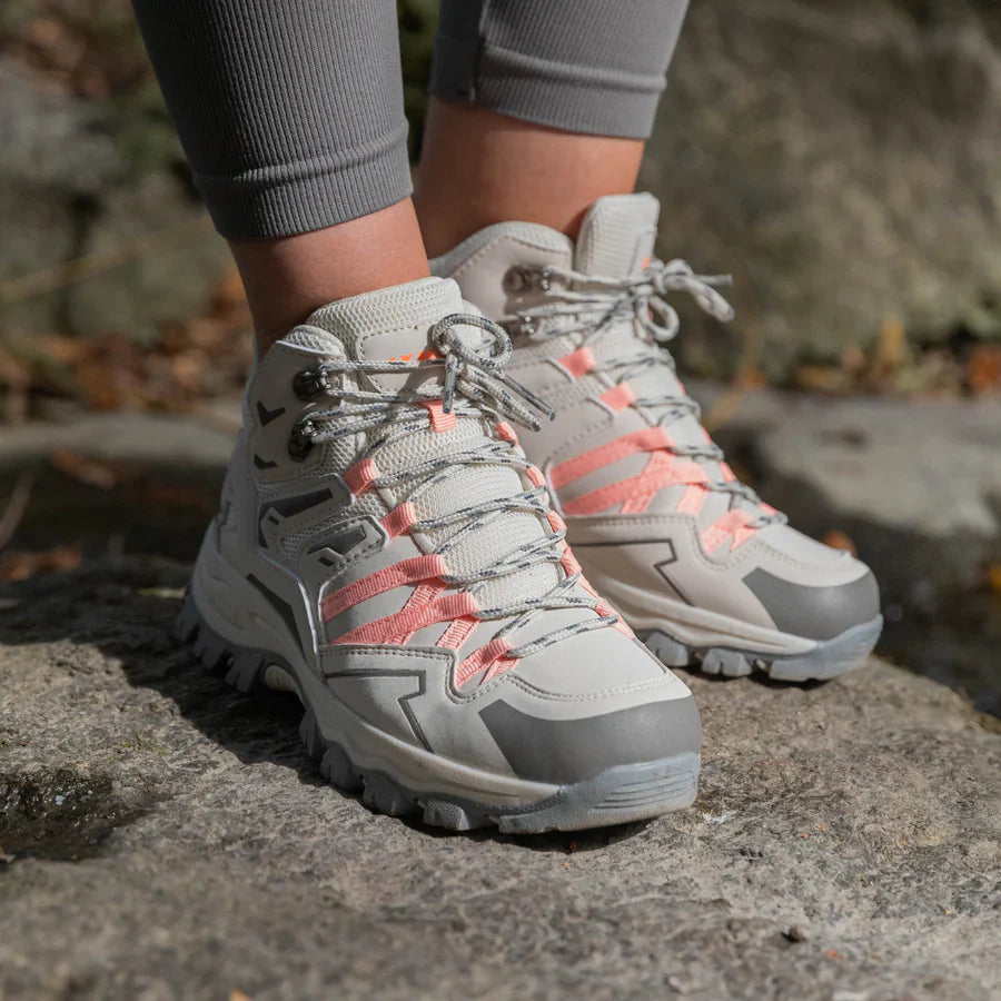 Gray hiking boots with pink accents worn by a person on a rocky surface.