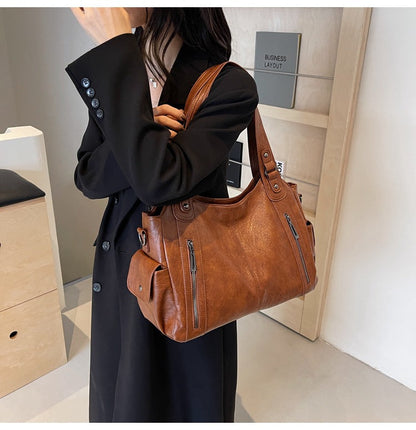 Person holding a brown leather handbag in an indoor setting