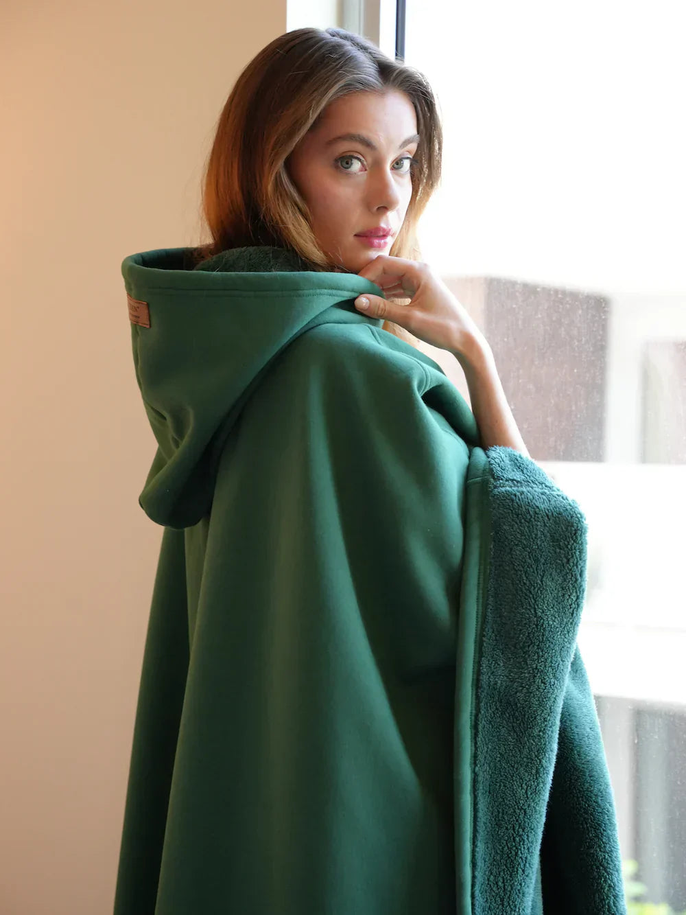 Woman holding a green fleece blanket indoors