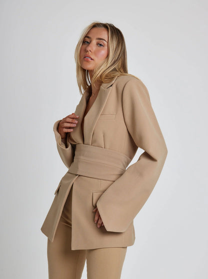 Woman wearing a beige suit against a white background