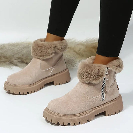Beige winter boots with fur trim worn by a person on a white background