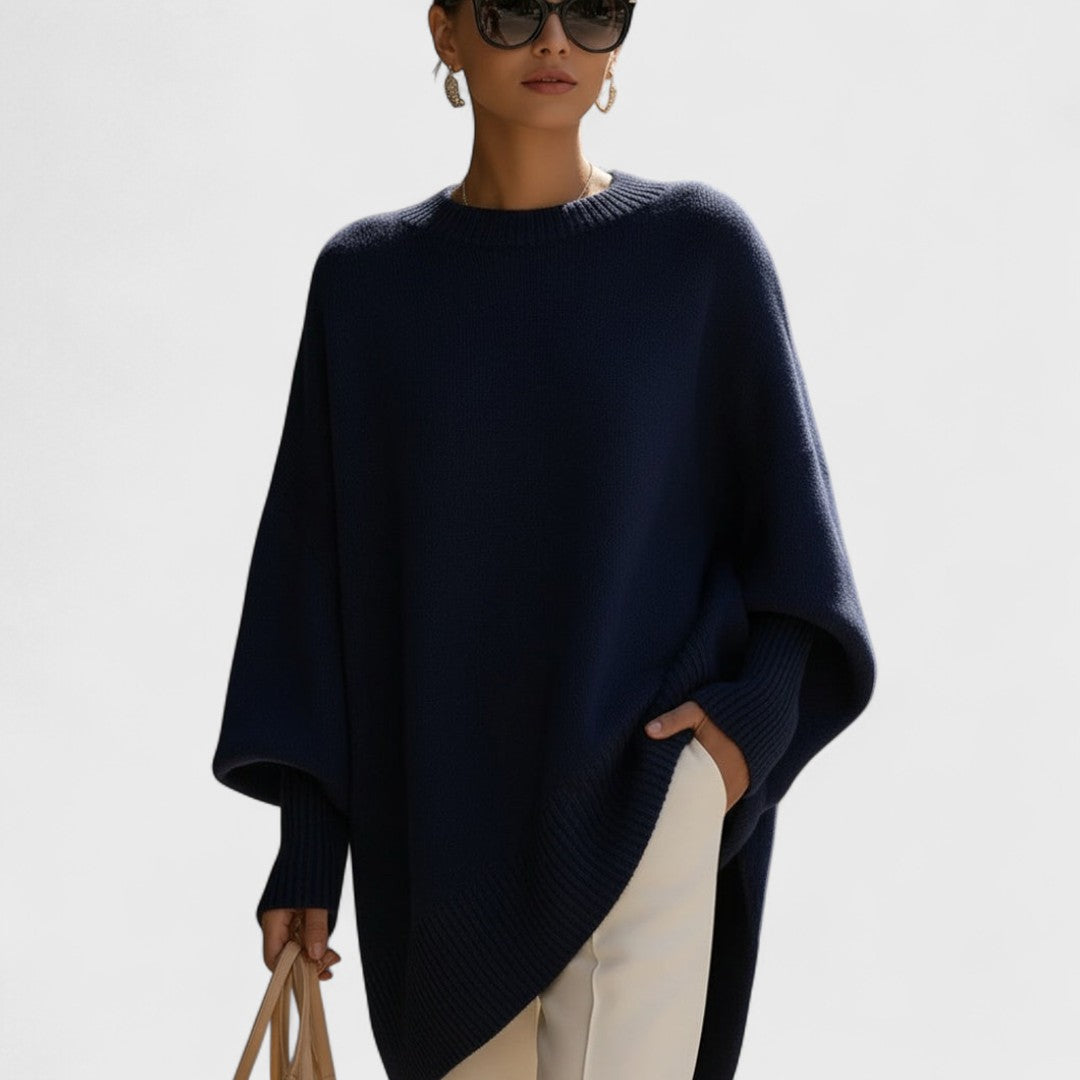 Woman wearing a navy blue poncho against a light background