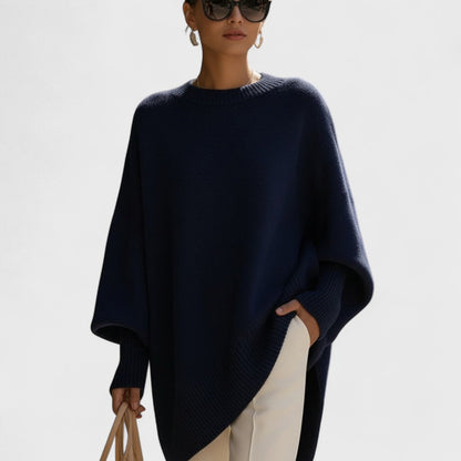 Woman wearing a navy blue poncho against a light background