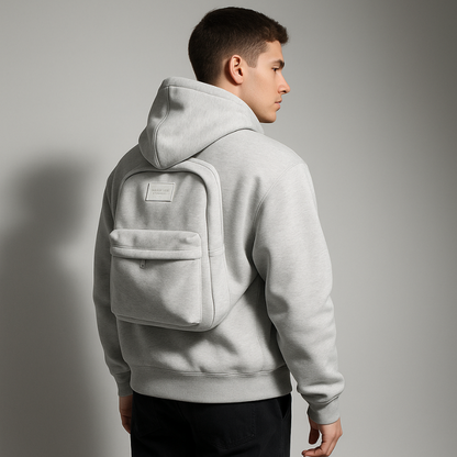 Person wearing a light gray hoodie with a backpack on a gray background