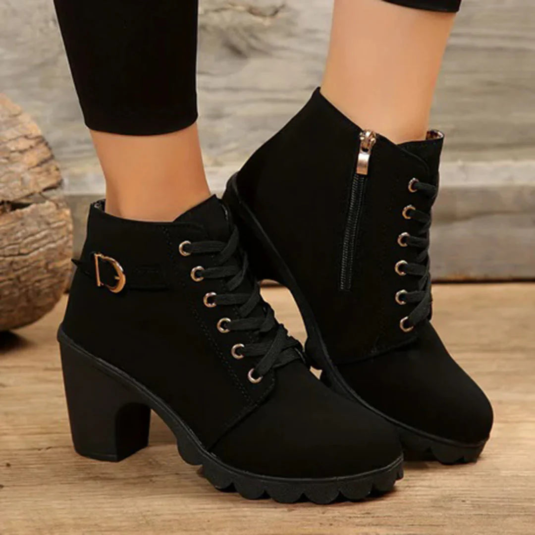 Black ankle boots with gold buckles on a wooden floor