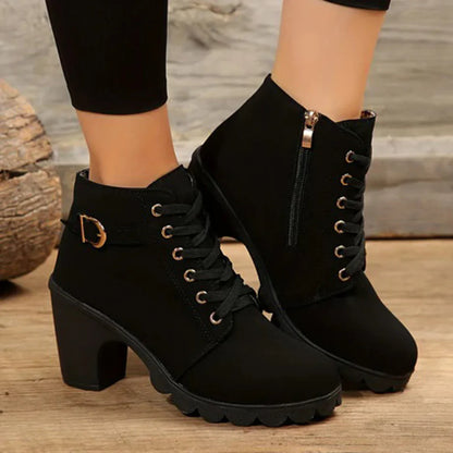 Black ankle boots with gold buckles on a wooden floor