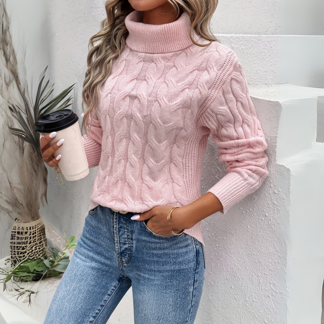 A woman models a pink cable-knit turtleneck sweater