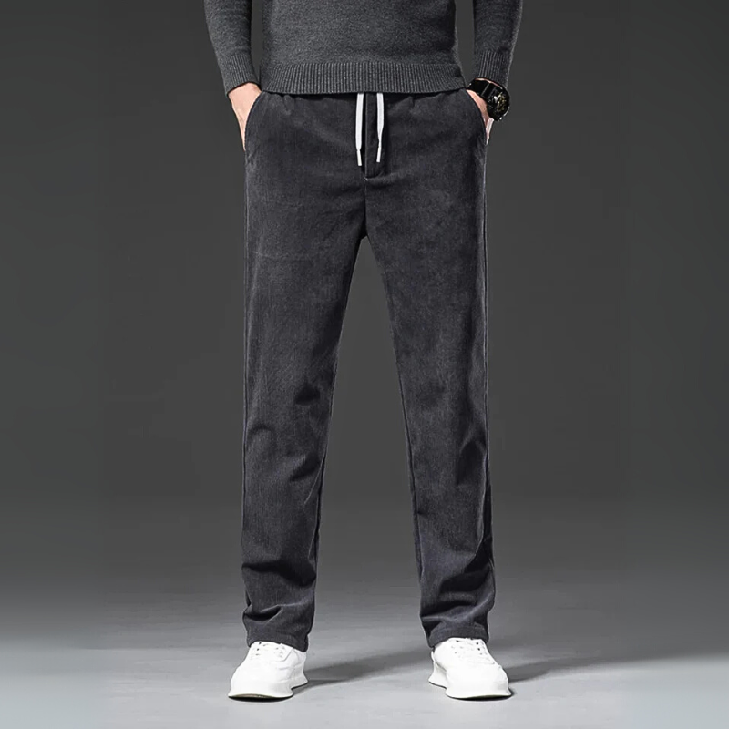Person wearing dark gray sweatpants with a plain background