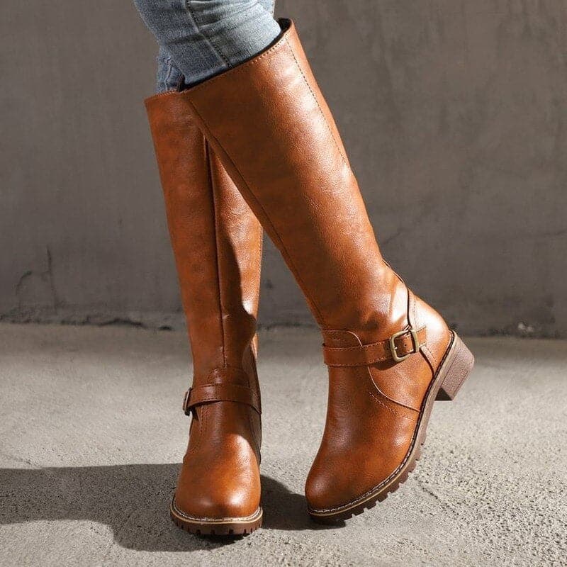 Brown knee-high boots with a strap on a neutral background