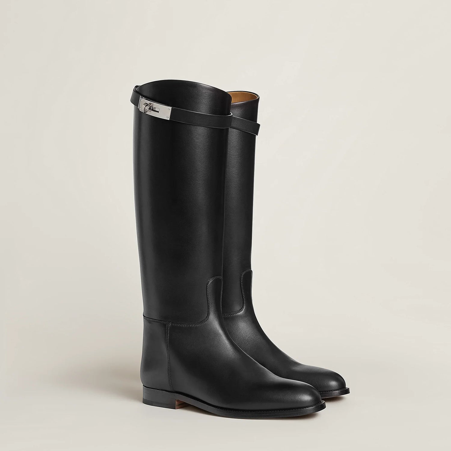 Pair of black riding boots on a light beige background